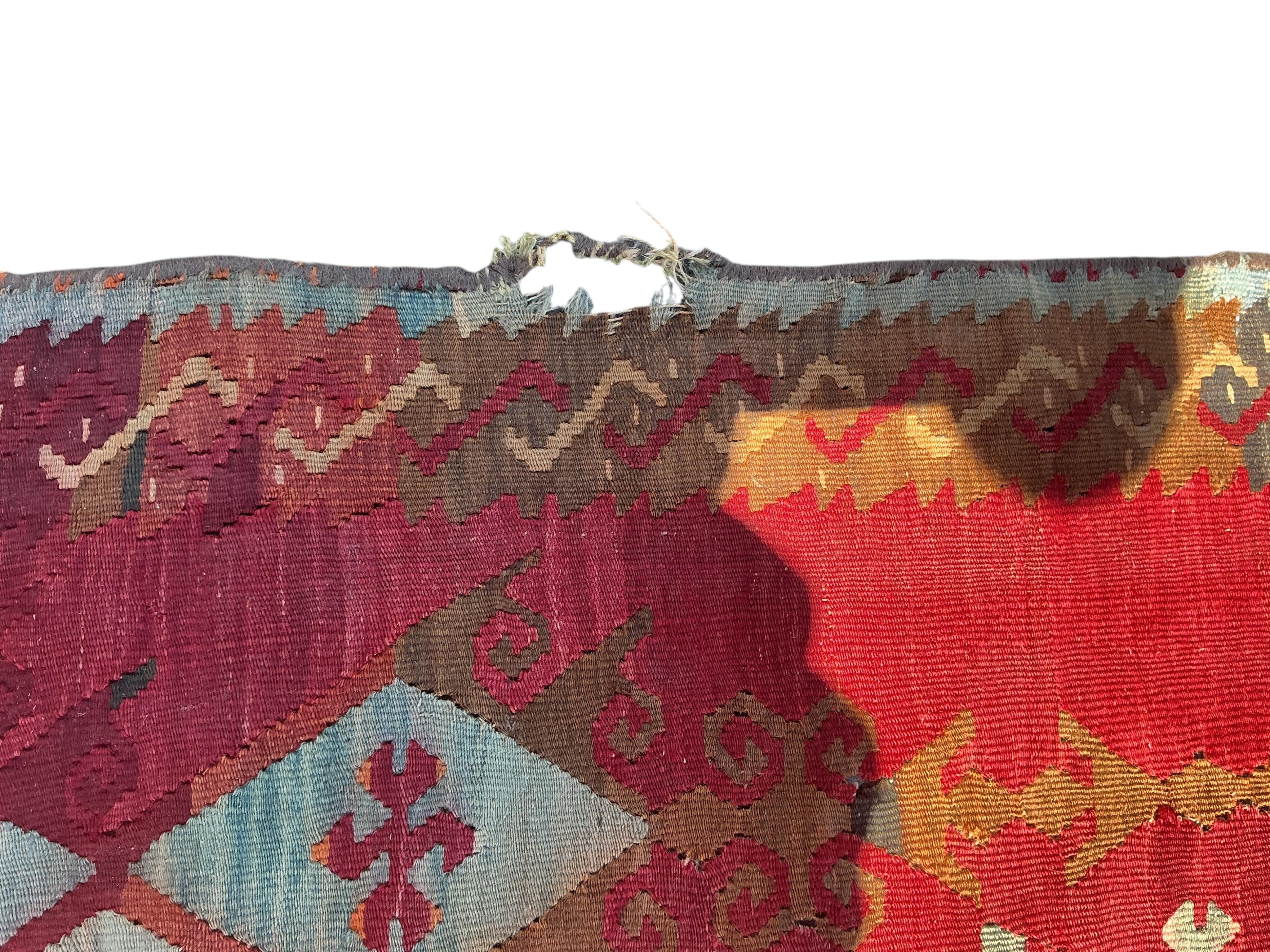 A Turkish Anatolian Kilim polychrome flatweave carpet, woven with geometric lozenges, on a pink field, 350 x 273cm